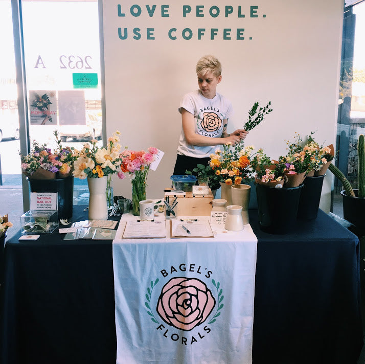 Bagel standing at a table filled with their flower arrangements